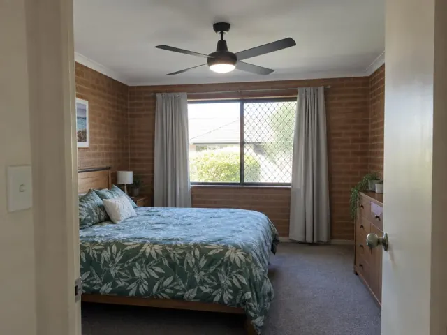 Bedroom with a black ceiling fan, brick walls and a window with curtains in Fletcher